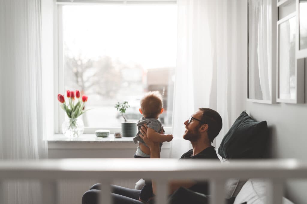 Pappa med ett barn tittar ut genom fönster